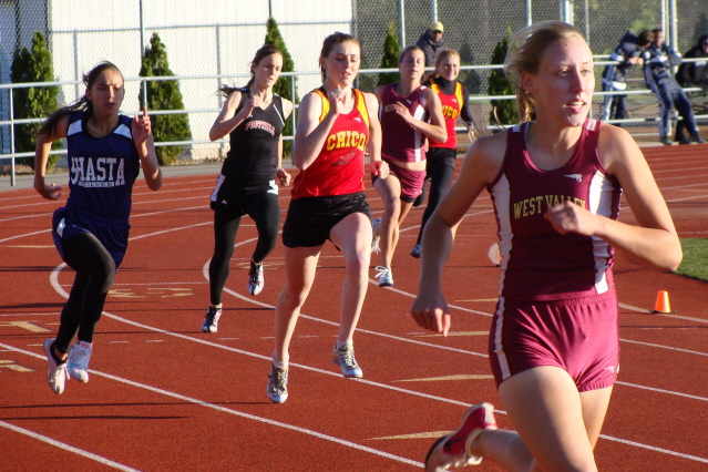 Chico's Kody Atkins (middle of the track) is out well coming off the first turn in the varsity girls 400m. She would win by a comfortable margin over West Valley's Cassie DeBonis (foreground far right) despite the cool, blustery conditions.