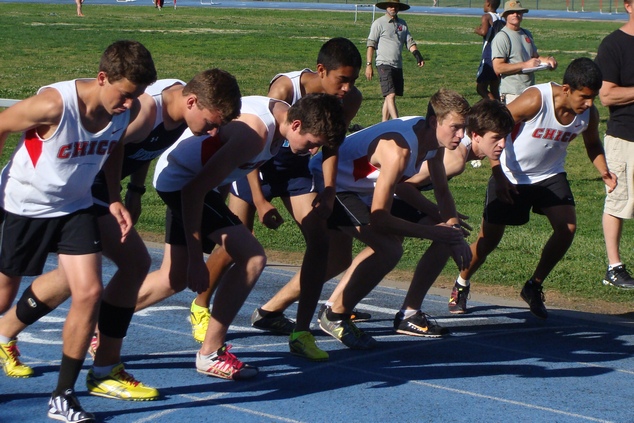 The field of the varsity boys 800m is focused on the starter.